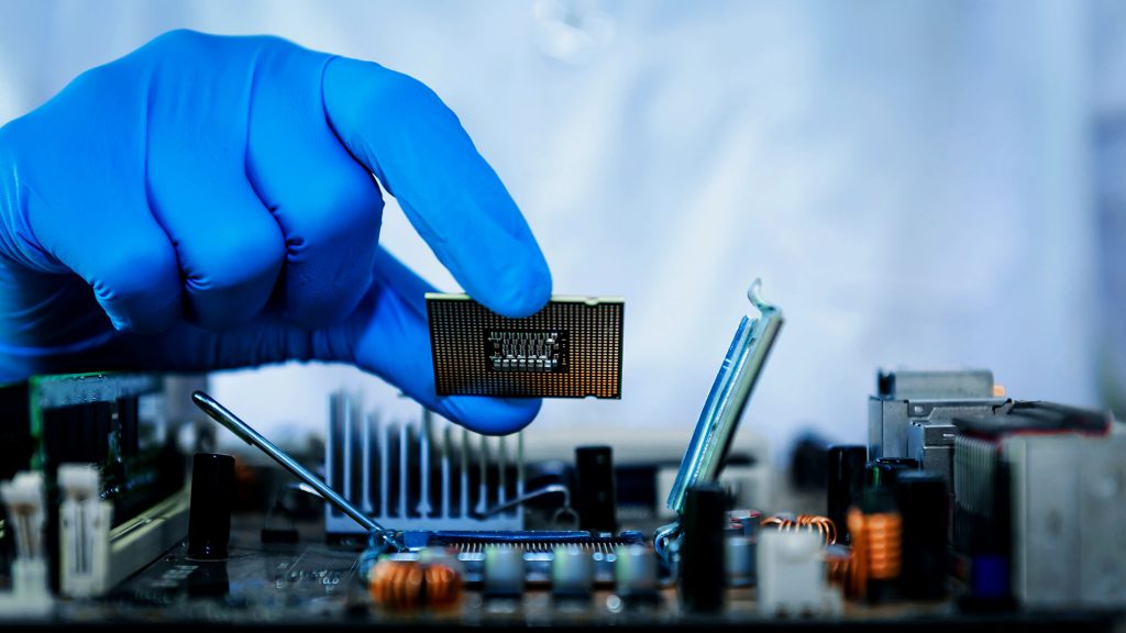 Photo of a gloved hand holding a microchip - Integrity Cleanroom